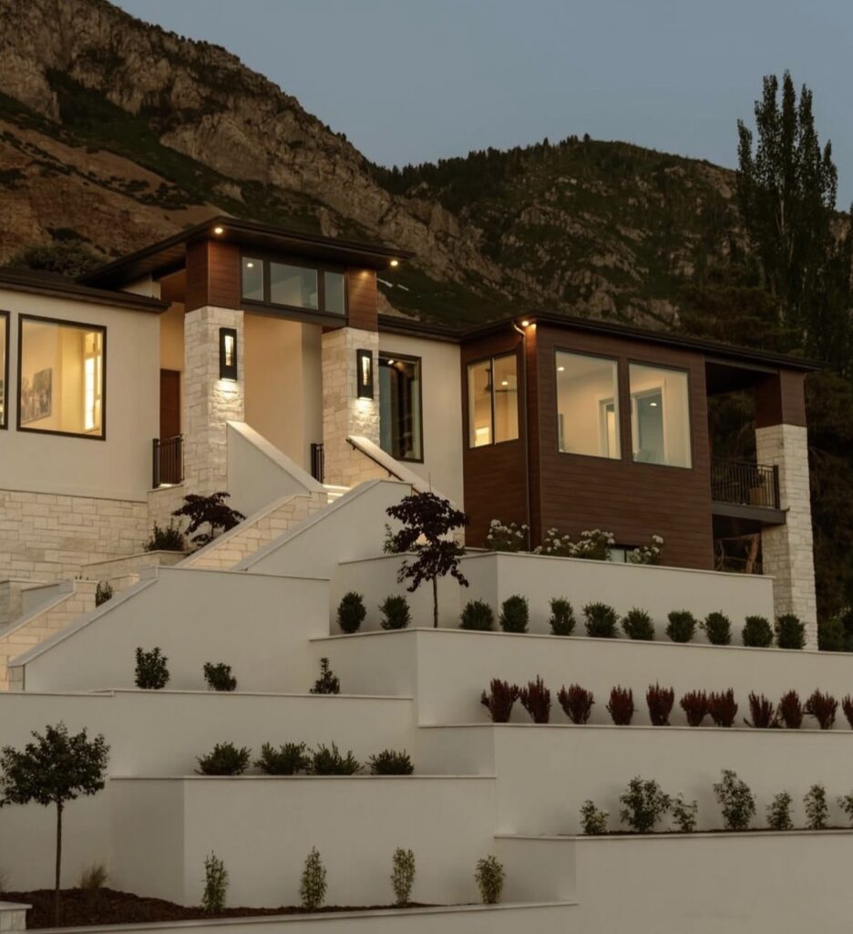 Tiered white retaining walls with integrated landscaping at a modern hillside home