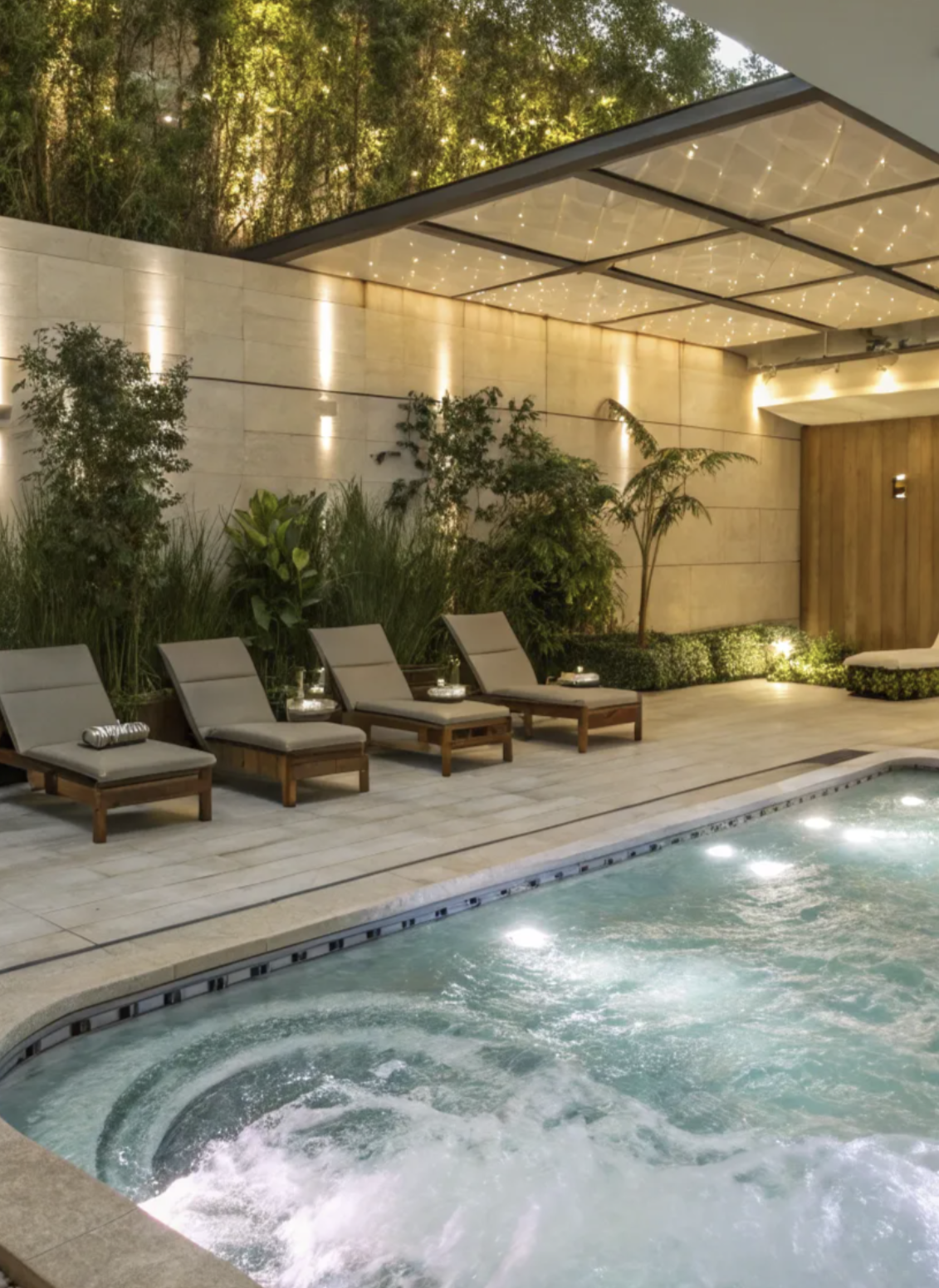 Modern luxury spa pool with in-pool lighting, wood accents, and ambient wall lights under a canopy of twinkling ceiling lights